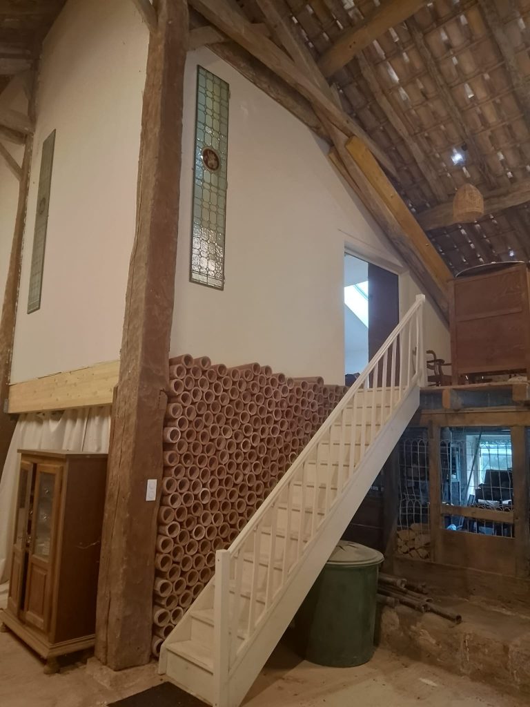 Intérieur de la grange du gîte, avec son escalier et ses vitraux anciens